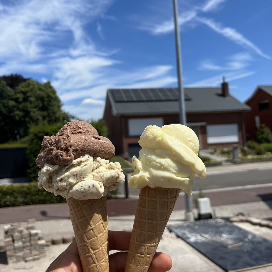 Twee hoorntjes met chocolade- en vanille-ijs tegen een blauwe lucht