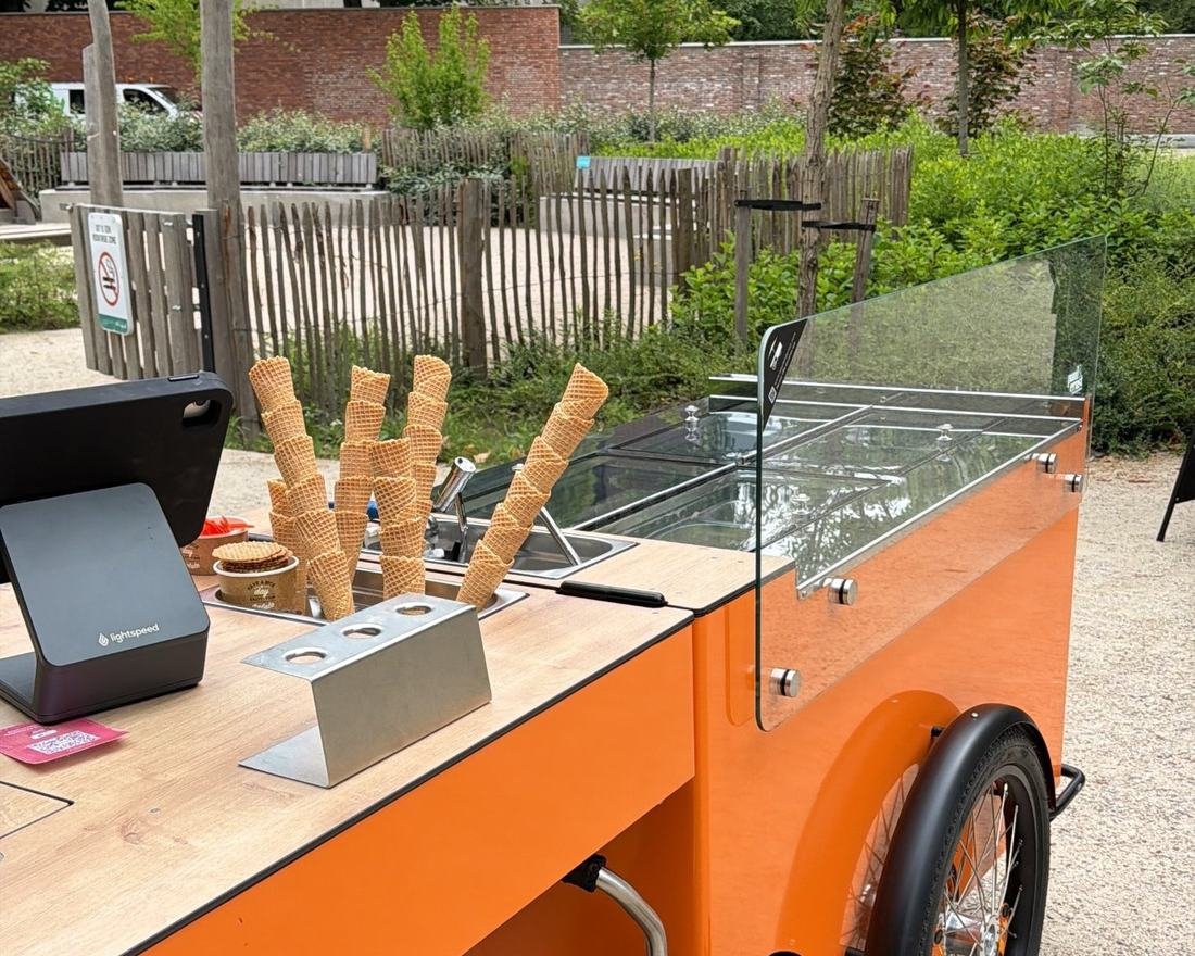 Onze oranje ijsfiets met hoorntjes en vitrine, opgesteld in het park